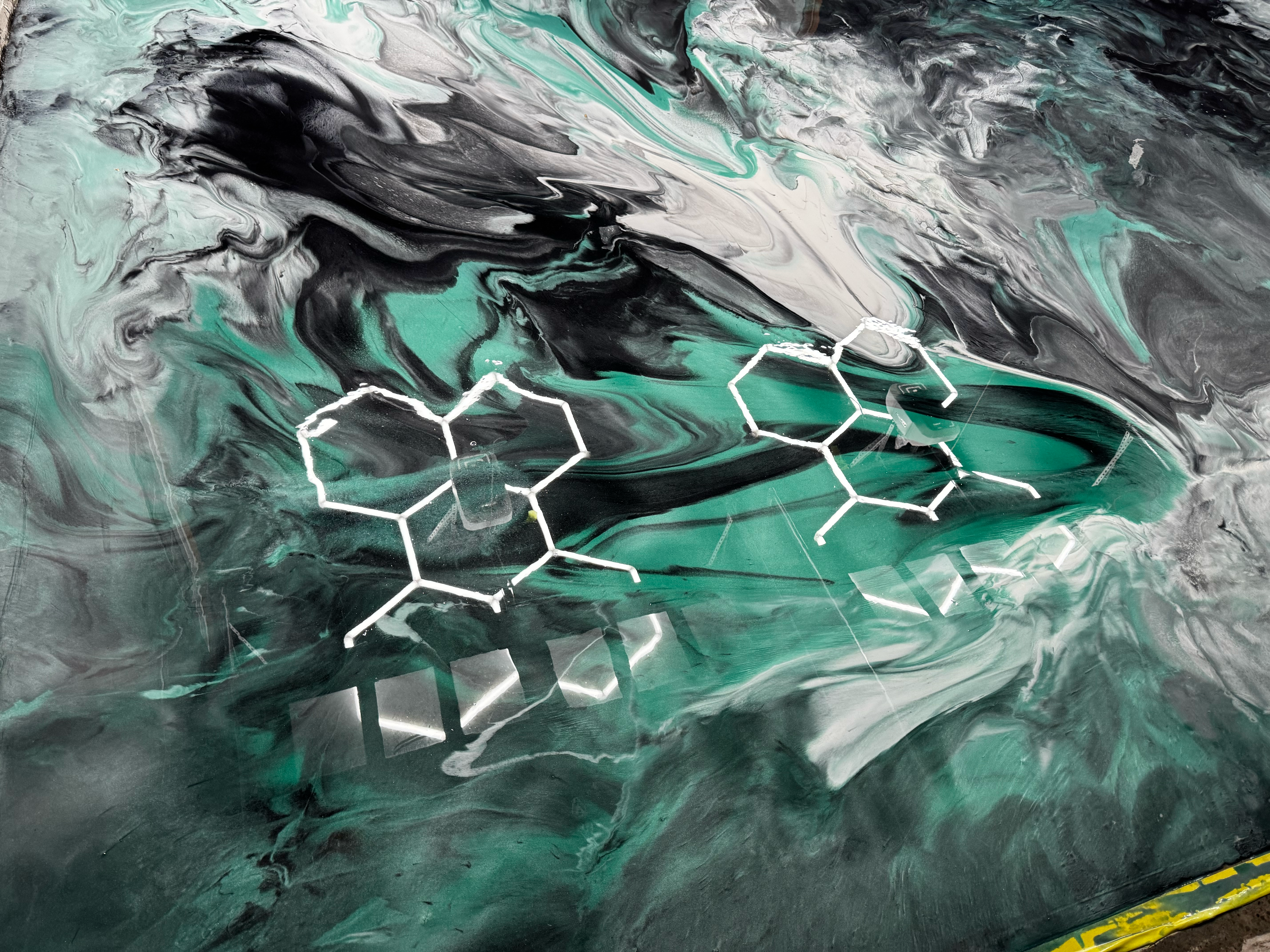 Metallic swirl epoxy garage floor in green, black, and white with chemical pattern design