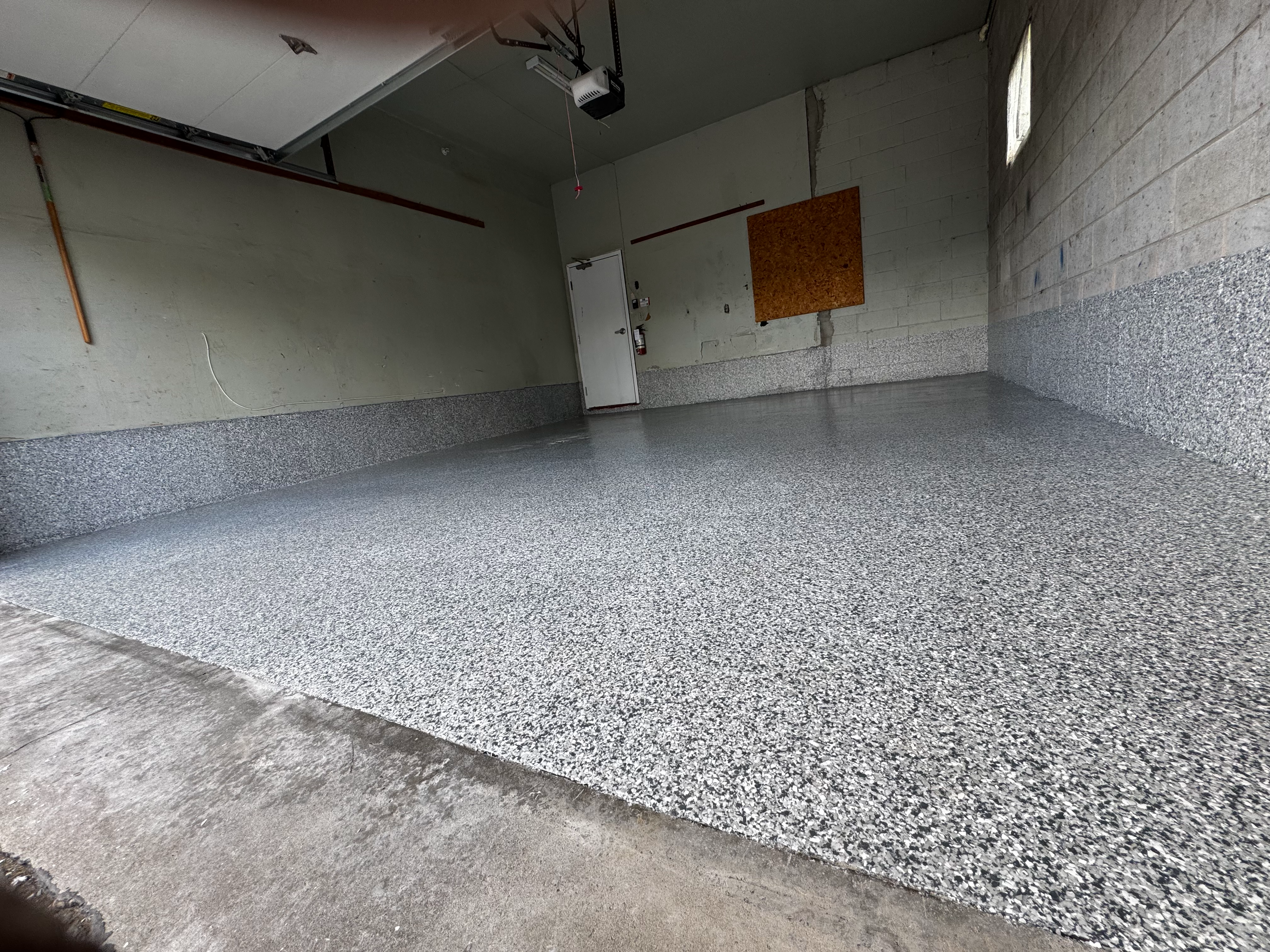 Flake epoxy garage floor with gray and white speckle finish across full space
