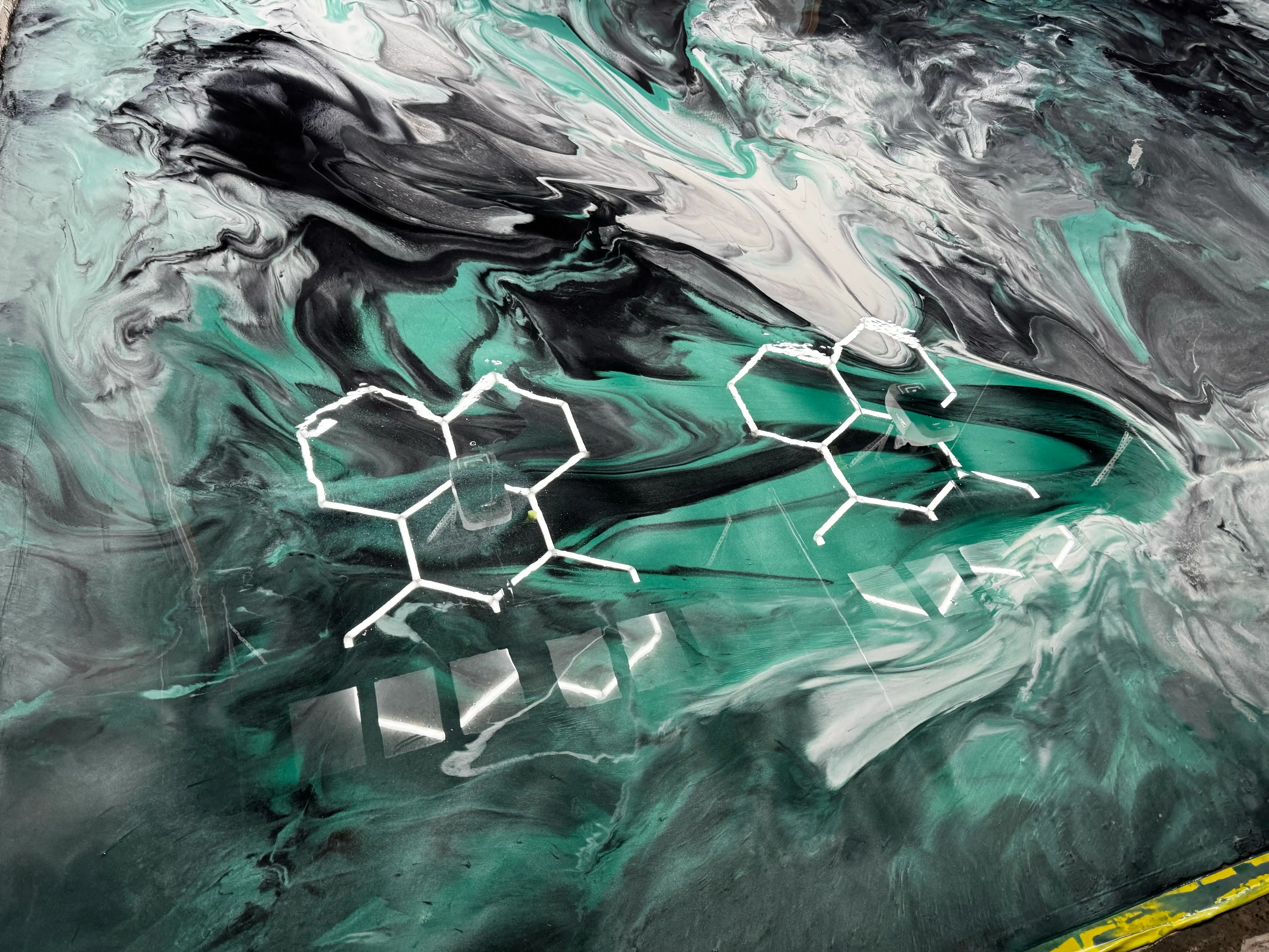 Metallic swirl epoxy garage floor in green, black, and white with chemical pattern design