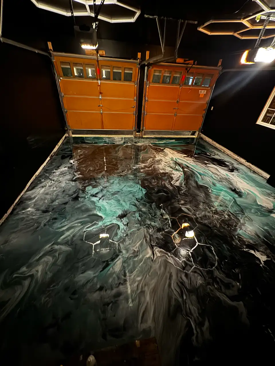 Metallic epoxy garage floor at night with lighting reflections on glossy surface