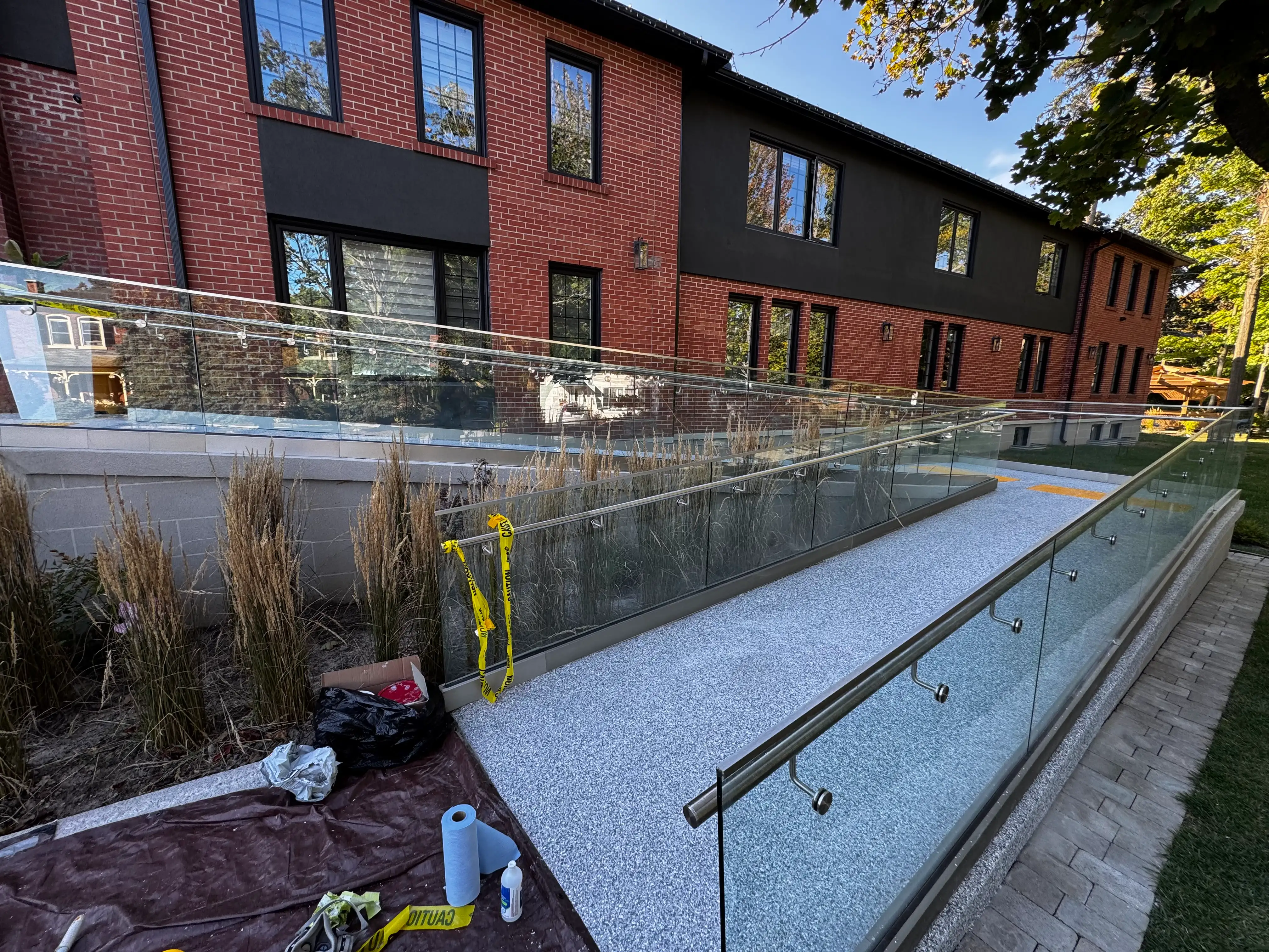 Outdoor wheelchair ramp finished with gray flake epoxy and glass railing