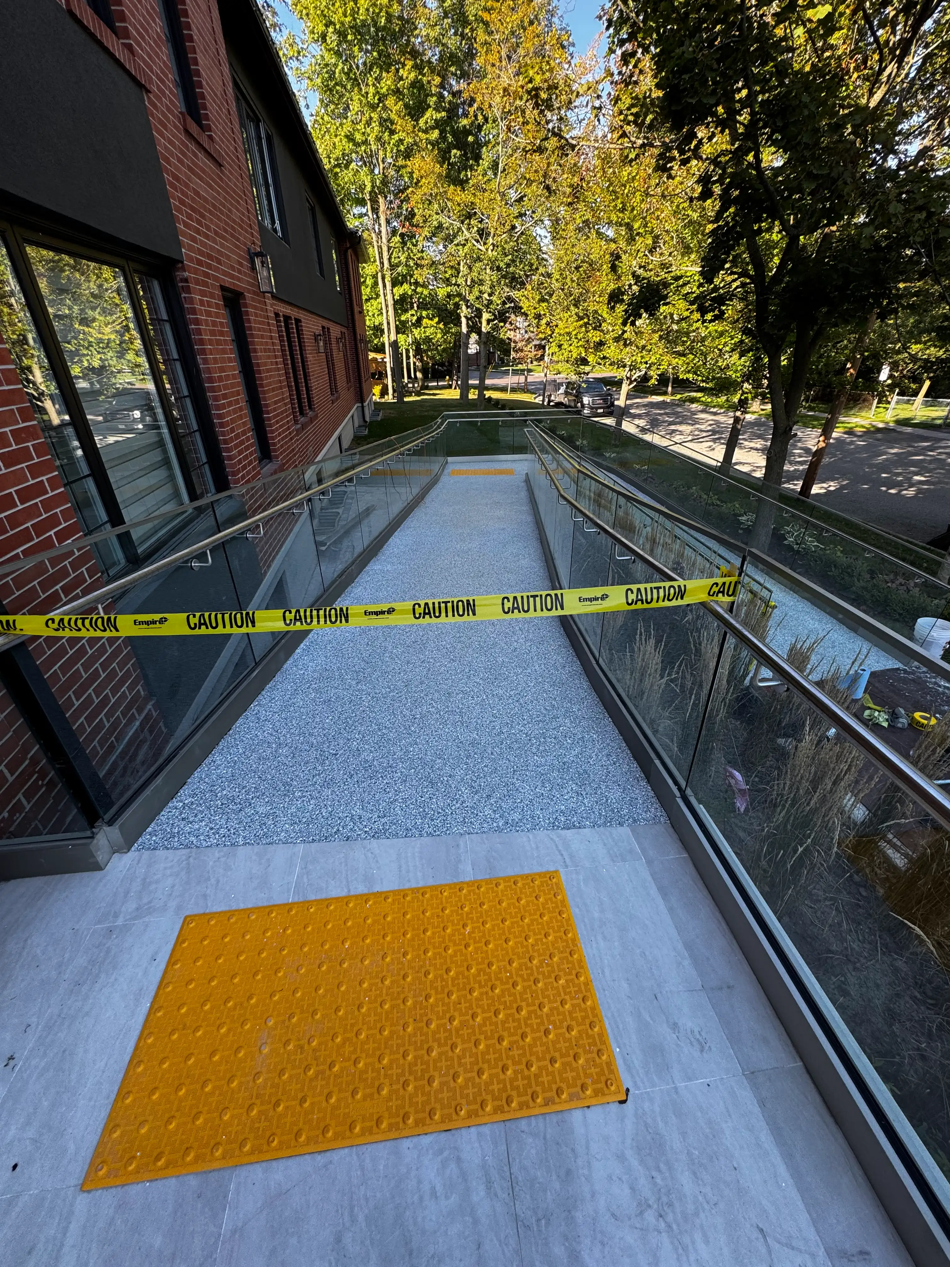 Epoxy wheelchair ramp with yellow tactile pad and caution tape during installation
