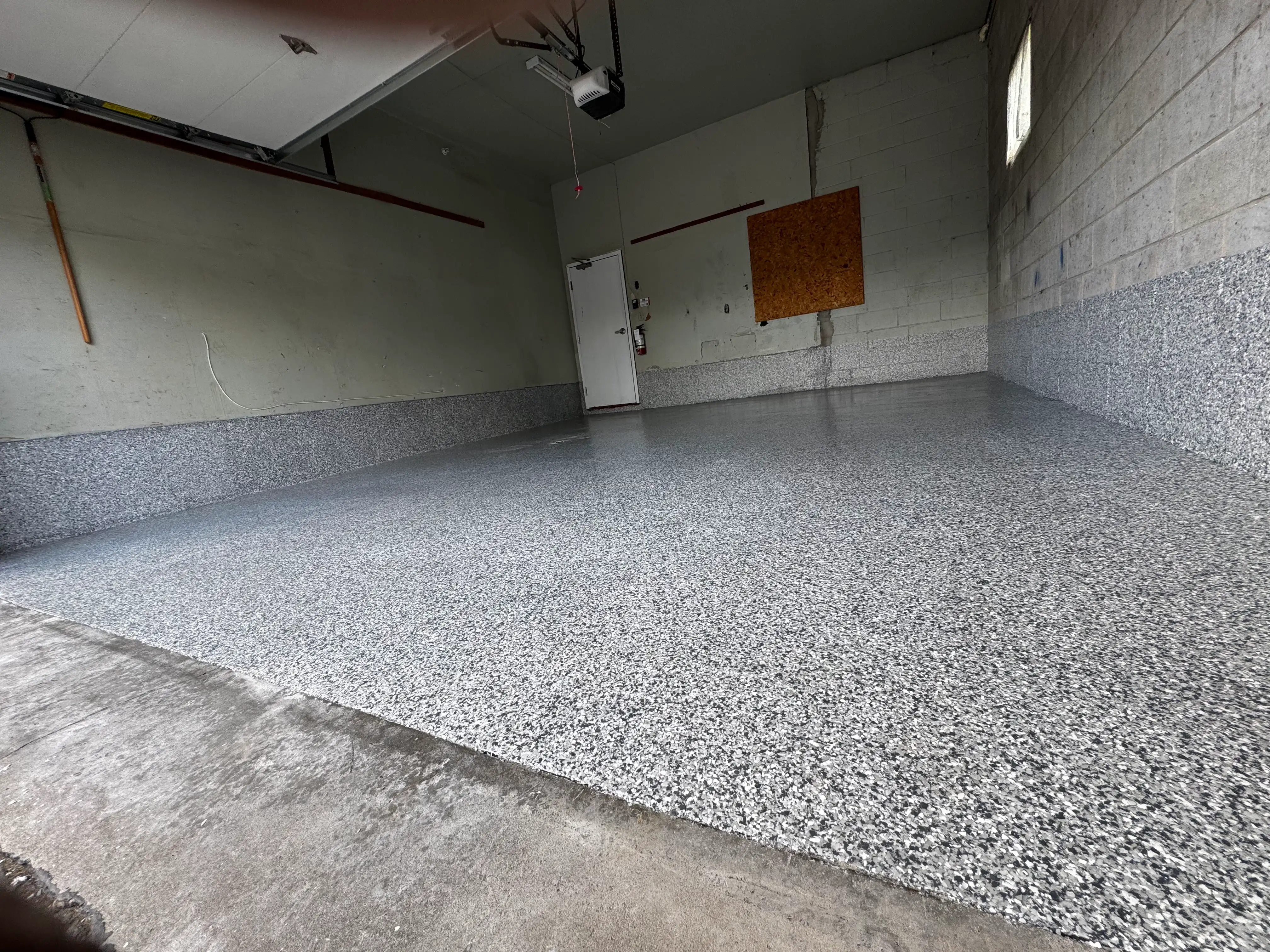 Flake epoxy garage floor with gray and white speckle finish across full space